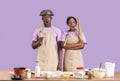 Shocked African American couple covered in flour baking together on color background