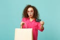 Shocked african girl in heart sunglasses hold package bag with purchases after shopping credit card isolated on blue Royalty Free Stock Photo