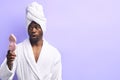 Shocked african man in bathrobe and towel looking at pink small mirror Royalty Free Stock Photo