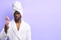 Shocked african man in bathrobe and towel looking at pink small mirror Royalty Free Stock Photo