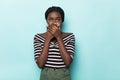 Shocked african woman covering her mouth and looking at the camera over blue background Royalty Free Stock Photo