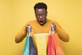 Shocked african young man holding shopping bags being surprises