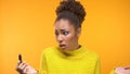 Shocked Afro-American young woman looking at lipstick, unsatisfied with color