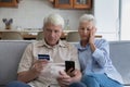 Shocked aged couple overspending money online using credit card phone