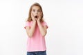 Shocked amazed cute little kid, blond teenage girl, gasping amazed speechless stare camera, touch face from shock, look Royalty Free Stock Photo