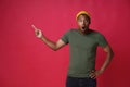 Shocked, amazed pointing one finger sideways left young african american man wearing khaki, green t-shirt and yellow hat Royalty Free Stock Photo