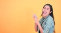 Shocked, amazed young beautiful asian woman 20s standing looking at camera with excited smile  on yellow background Royalty Free Stock Photo