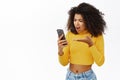 Shocked, angry african american girl, reacts on smth frustrating on mobile phone, complaining on smartphone text
