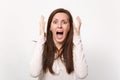 Shocked angry scared young woman in light clothes screaming keeping mouth wide open holding hands near face isolated on