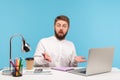 Shocked annoyed man office worker spreading hands looking at camera with astonishment, sitting at workplace with laptop and coffee Royalty Free Stock Photo