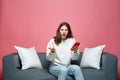 Shocked annoyed young woman holds phone irritated by by bad news or spam in message online, sitting on sofa Royalty Free Stock Photo