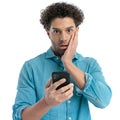 shocked arab man with curly hair holding phone and reading emails Royalty Free Stock Photo