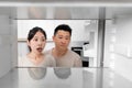 Shocked asian couple looking inside empty fridge at home Royalty Free Stock Photo