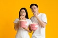 Shocked asian guy and girl eating popcorn, watching movie Royalty Free Stock Photo