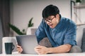 Shocked Asian man in eyeglasses looking at laptop sitting on the couch in the living room Royalty Free Stock Photo