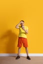 Young caucasian man using smartphone. Full body length portrait isolated over yellow background. Royalty Free Stock Photo