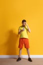 Young caucasian man using smartphone. Full body length portrait isolated over yellow background. Royalty Free Stock Photo