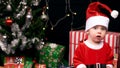 Shocked baby in santa outfit for christmas decorations and tree