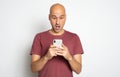 Shocked bald man is reading unbelievable news on his smartphone Royalty Free Stock Photo