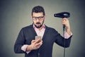 Shocked man checking his phone holding a hair dryer Royalty Free Stock Photo