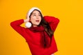 Shocked beautiful Asian girl wearing christmas hat isolated on yellow background. She covered both ears with her hands Royalty Free Stock Photo
