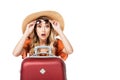 shocked beautiful girl holding sunglasses and sitting near travel bag