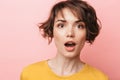 Shocked beautiful woman posing isolated over pink wall background