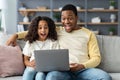 Shocked black dad and daughter using computer at home