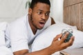 Shocked Black Guy Looking At Alarm-Clock Waking Up Oversleeping Indoors Royalty Free Stock Photo