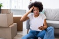 Shocked Black Lady Reading Bill Sitting Among Moving Boxes Indoor