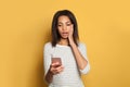 Shocked black woman lookin at cell phone on colorful yellow background Royalty Free Stock Photo