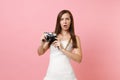 Shocked bride woman in white wedding dress holding retro vintage photo camera, choosing staff, photographer on