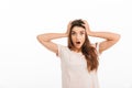 Shocked brunette woman in t-shirt holding her head