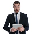 Shocked businessman holding tablet and gasping