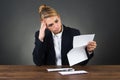 Shocked Businesswoman Reading Letter At Desk