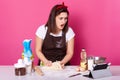 Shocked Caucasian women baking with recipe on tablet, stand with opened mouth, has surprised facial expession, kneads dough, Royalty Free Stock Photo