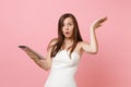 Shocked concerned bride woman in white wedding dress spreading hands hold working on tablet pc computer on Royalty Free Stock Photo