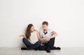 Shocked couple using laptop, sitting on floor