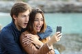 Shocked couple watching a smart phone on holidays Royalty Free Stock Photo