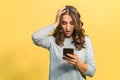 Shocked attractive woman with a smartphone, isolated on yellow Royalty Free Stock Photo