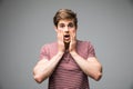 Shocked dazed young man holding head with both hands over grey background Royalty Free Stock Photo