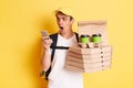 Shocked delivery man wearing t shirt and cap holding pizza boxes and takeaway drink, posing isolated over yellow background,