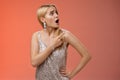 Shocked displeased bothered arrogant blond glamour woman in silver glittering dress turning upper right corner pointing