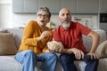 Shocked elderly couple sitting on couch with bowl of popcorn, watching tv Royalty Free Stock Photo