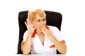 Shocked elderly female doctor or nurse sitting behind the desk and overhears a conversation Royalty Free Stock Photo
