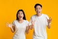 Shocked emotional asian couple on yellow background