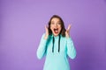 Shocked emotional young woman posing isolated over purple background wall