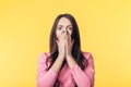 Shocked excited woman covering her mouth with hands on yellow background