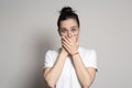 Shocked, frightened woman covers her mouth with her hands and looks into the camera with big eyes. Isolated on white background Royalty Free Stock Photo