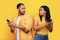 Shocked frightened young african american man and woman with smartphones looking at each other Royalty Free Stock Photo